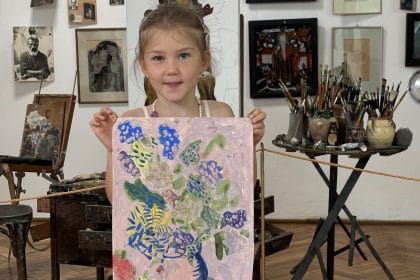 O fetiță ține în brațe un tablou cu flori, pictat de ea, într-un atelier de creație la Muzeul de Artă Constanța