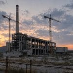 Ilustrație generată cu AI: o centrală pe cărbune abandonată, în construcție neterminată, la apus